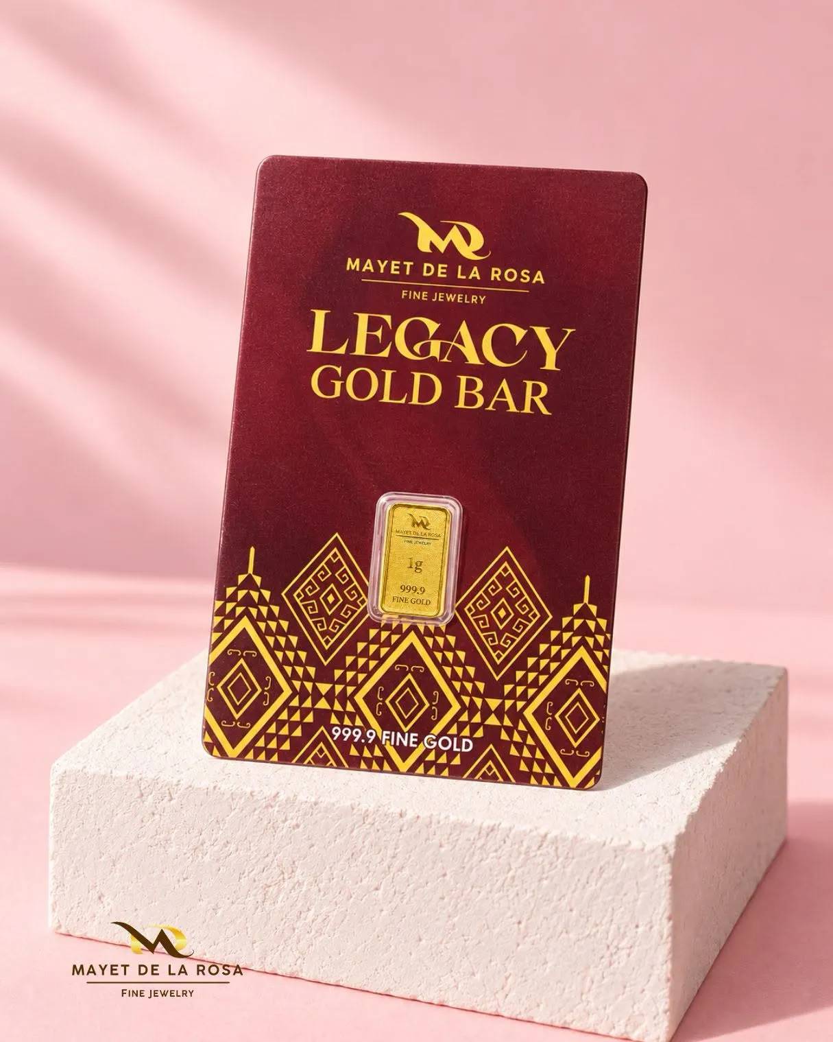 A 1 g Legacy Gold Bar card standing on a pale stone block against a pink backdrop