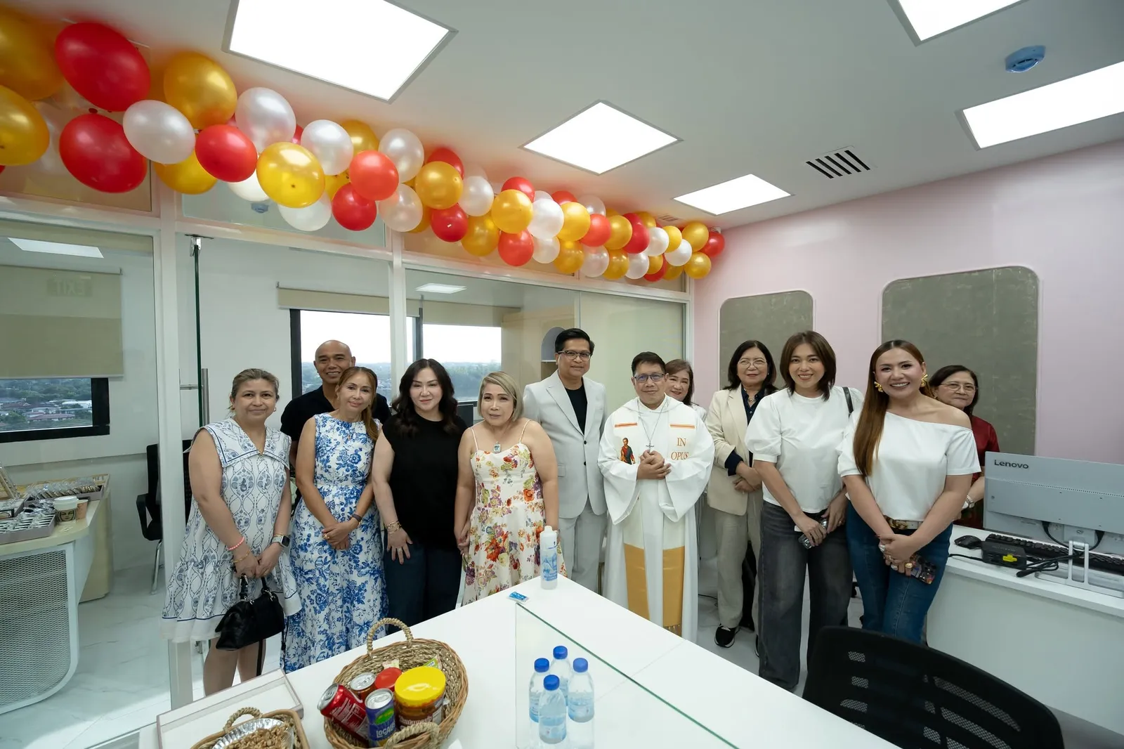 Guests and staff gathered under gold, red and white balloons in the new studio space