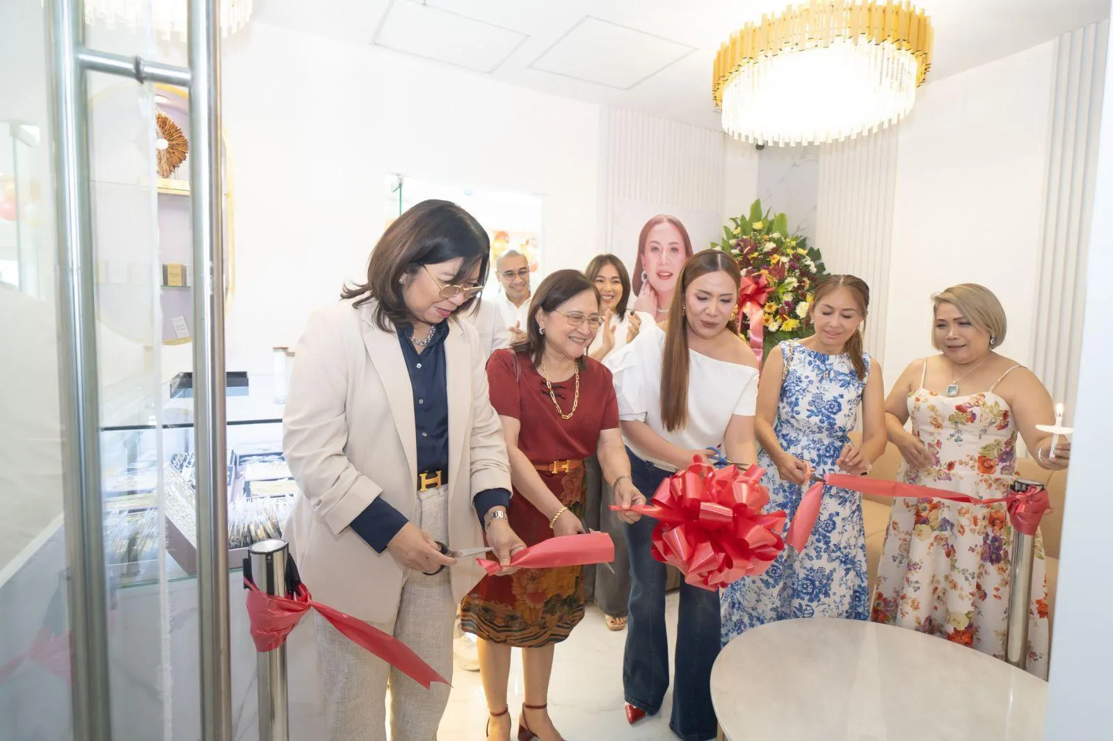 Founders and guests cutting the red ribbon at the opening of Mayet Live House, under a gold chandelier