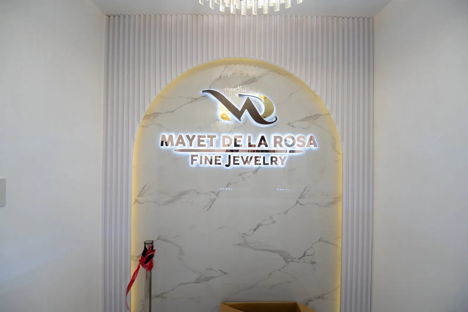 The illuminated Mayet De La Rosa Fine Jewelry sign on a white marble arch